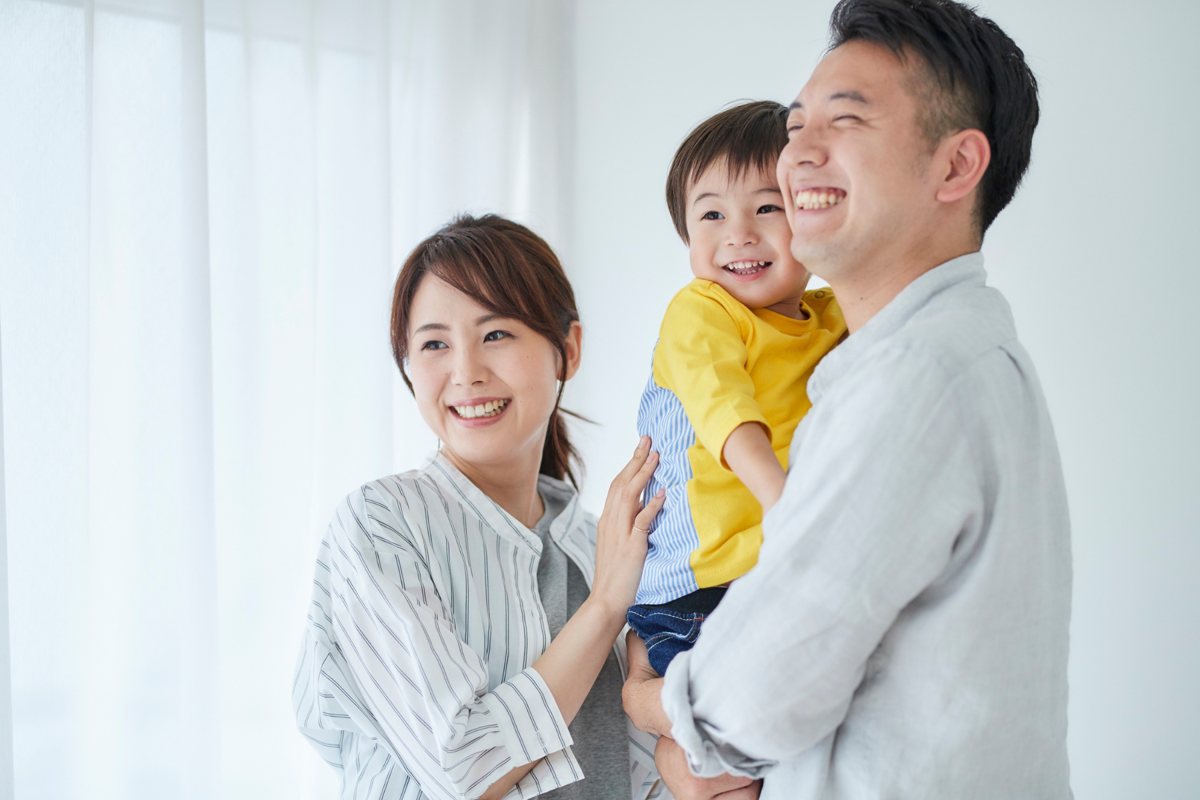 子どもを抱いて笑う夫婦