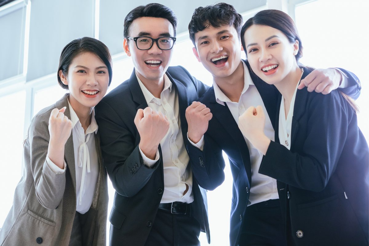 こぶしを握って笑う若い社会人たち